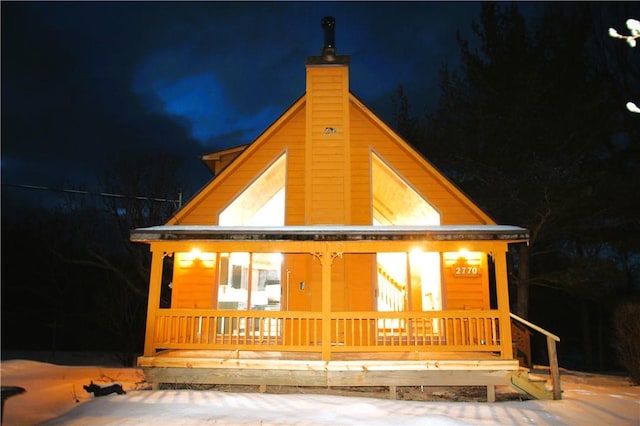 back of house at twilight featuring a porch