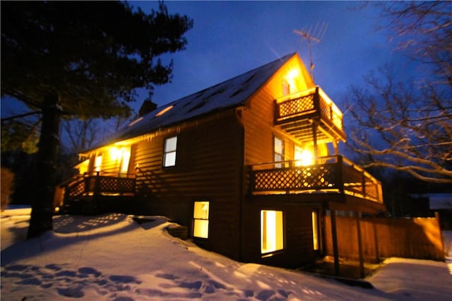 snow covered property with a balcony and a wooden deck