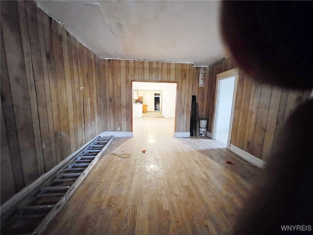 corridor with hardwood / wood-style floors and wooden walls