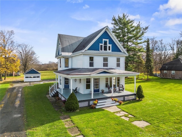 farmhouse inspired home with a front yard, a porch, and an outdoor structure