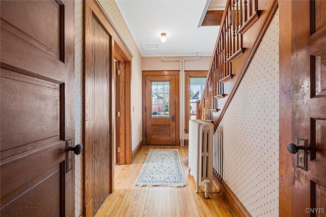 entryway with light hardwood / wood-style floors, radiator, and crown molding