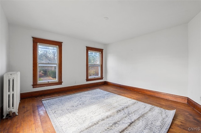 empty room featuring radiator heating unit, dark hardwood / wood-style floors, and a healthy amount of sunlight