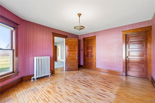 empty room featuring radiator and light hardwood / wood-style flooring