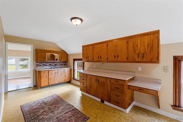 kitchen featuring vaulted ceiling, a wealth of natural light, sink, and backsplash