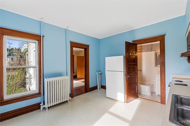 bedroom featuring ensuite bath, sink, radiator heating unit, and white refrigerator