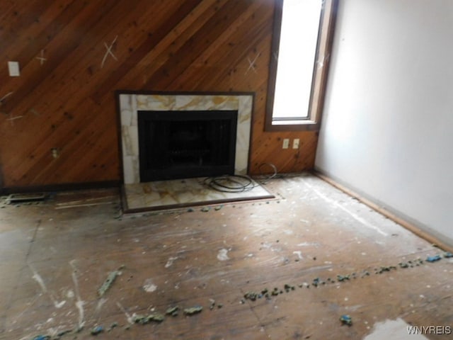 unfurnished living room with lofted ceiling and wooden walls