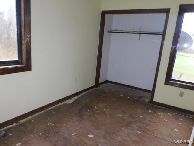 unfurnished bedroom featuring a closet and multiple windows