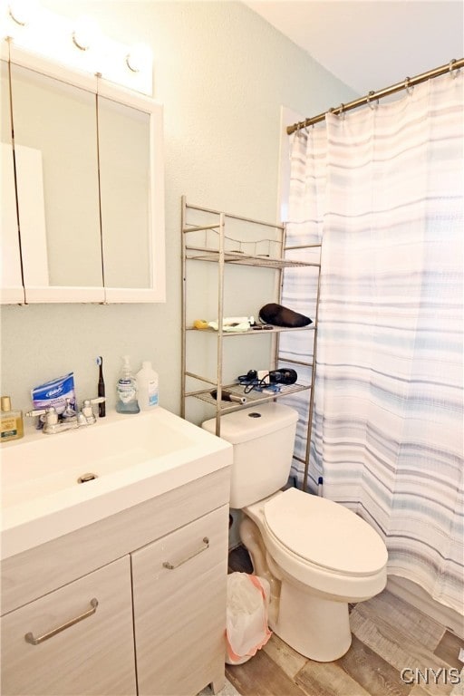 bathroom with hardwood / wood-style floors, vanity, a shower with shower curtain, and toilet