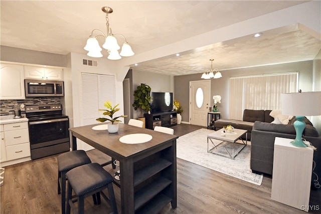 kitchen featuring a chandelier, pendant lighting, stainless steel appliances, and dark hardwood / wood-style floors