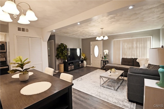 living room with a textured ceiling, a chandelier, and dark hardwood / wood-style floors