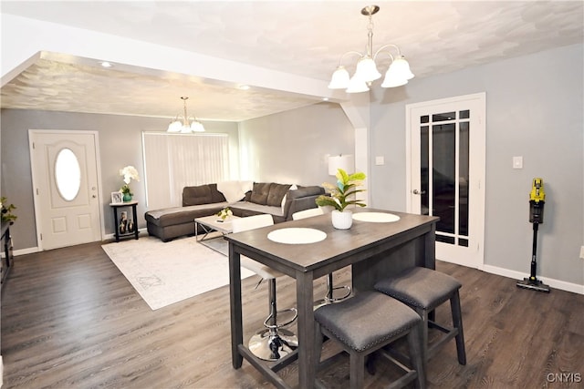 dining area featuring dark wood-type flooring and an inviting chandelier