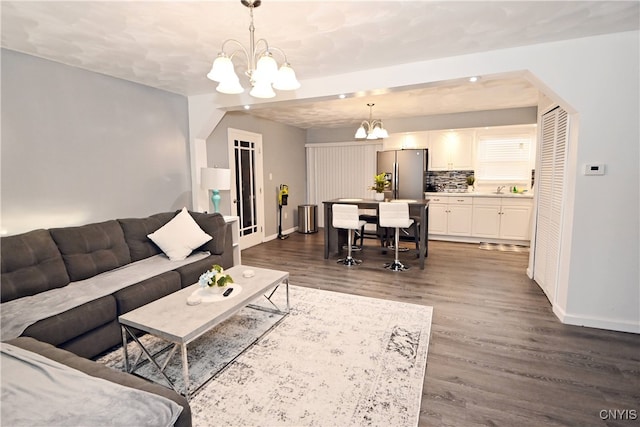 living room featuring sink, dark hardwood / wood-style flooring, and a notable chandelier