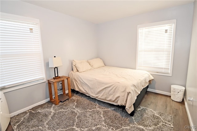 bedroom featuring multiple windows and dark hardwood / wood-style flooring