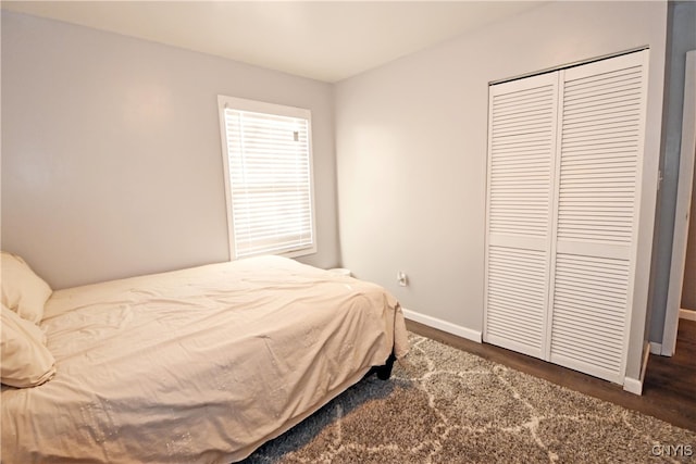 bedroom with dark hardwood / wood-style flooring and a closet