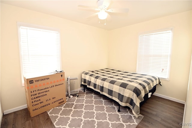 bedroom with ceiling fan, radiator heating unit, and dark wood-type flooring