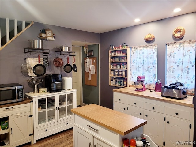 kitchen with hardwood / wood-style floors, wood counters, and white cabinets