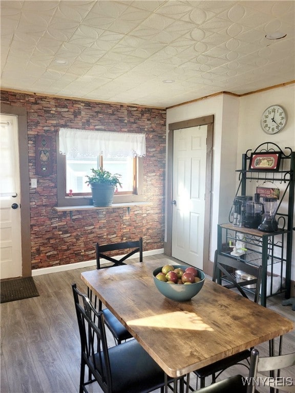 dining room featuring hardwood / wood-style flooring and brick wall