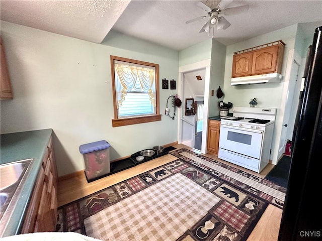 kitchen with ceiling fan, a textured ceiling, and gas range gas stove