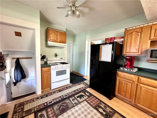 kitchen featuring ceiling fan, black fridge, light wood-type flooring, and gas range gas stove