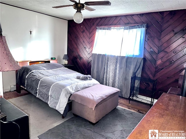 bedroom featuring a baseboard radiator, ceiling fan, and wooden walls