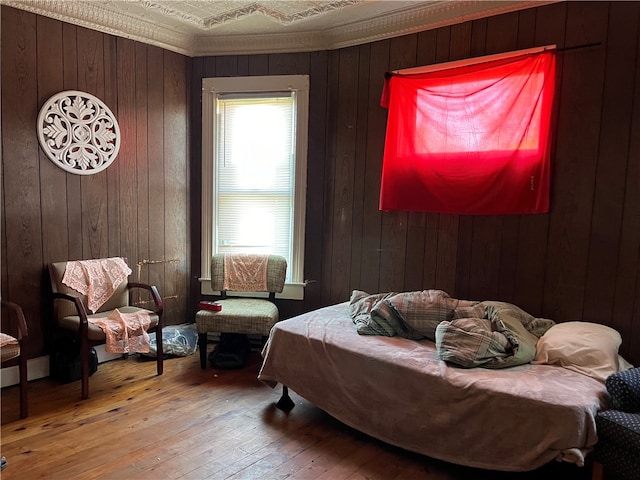 bedroom with wood walls, wood-type flooring, and crown molding