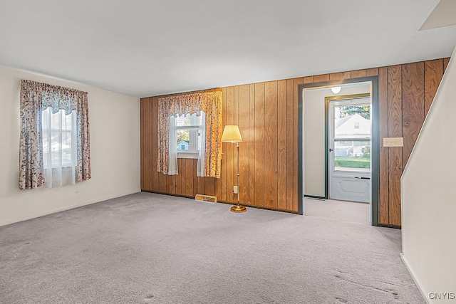 spare room with wooden walls and light colored carpet