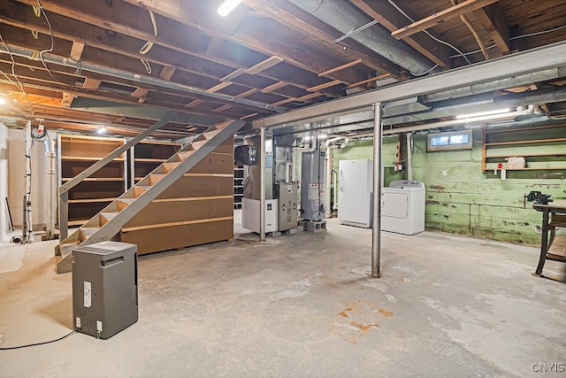 basement featuring washer and clothes dryer, white refrigerator, gas water heater, and heating unit