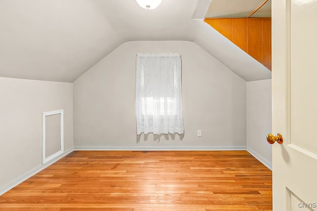 additional living space with light hardwood / wood-style flooring and lofted ceiling