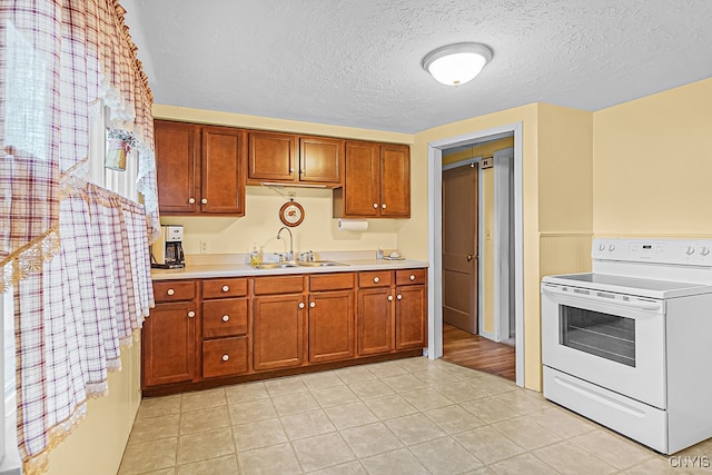 kitchen with electric range, light tile patterned flooring, sink, and a textured ceiling