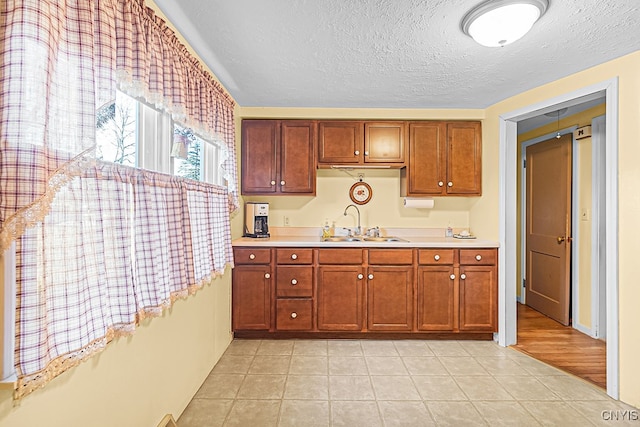 kitchen featuring a textured ceiling, light tile patterned flooring, and sink