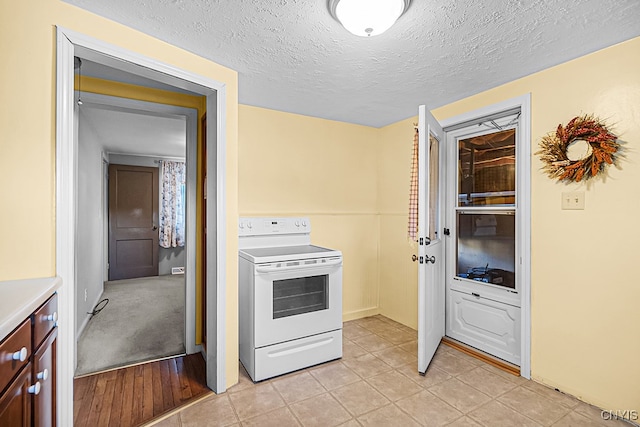 kitchen with light tile patterned floors, a textured ceiling, and white range with electric stovetop