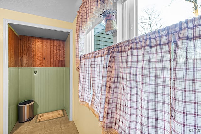 details with a textured ceiling, tile patterned floors, and wood walls