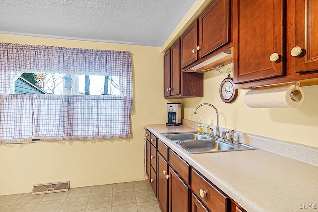 kitchen with a textured ceiling, light tile patterned floors, and sink