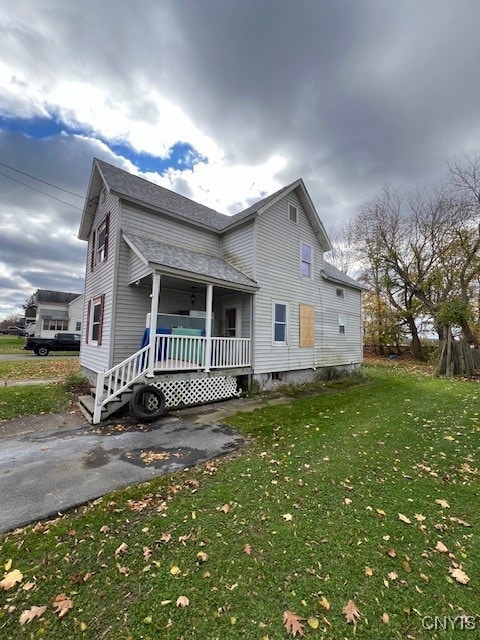 view of side of property with a lawn and covered porch