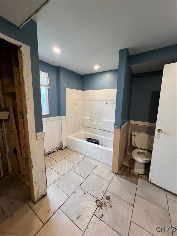 bathroom with a tub to relax in and toilet