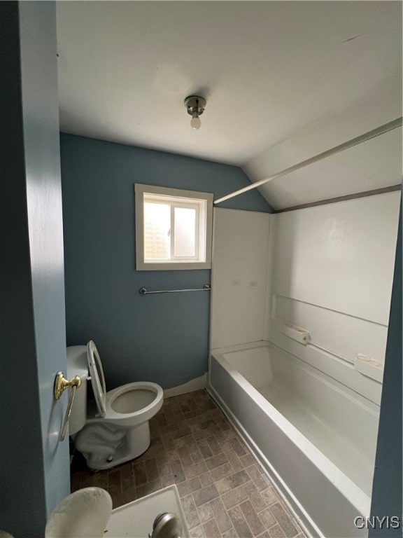 bathroom featuring  shower combination, toilet, and vaulted ceiling