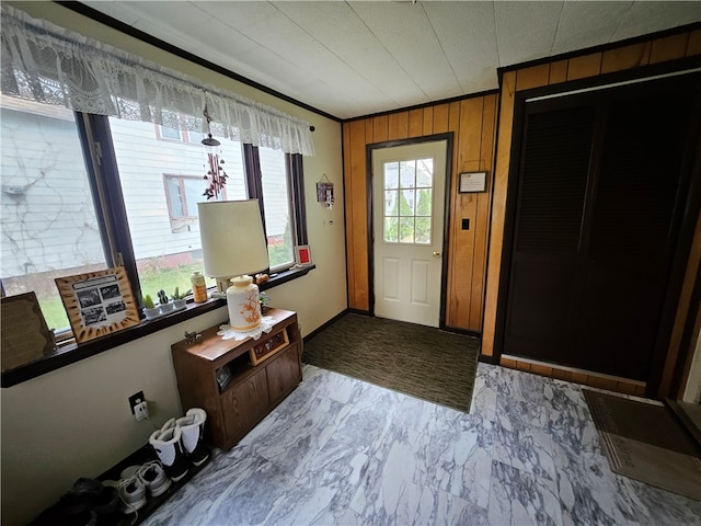 foyer entrance featuring wooden walls and crown molding