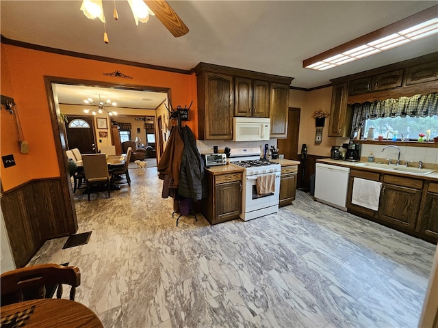 kitchen with dark brown cabinetry, sink, crown molding, white appliances, and ceiling fan with notable chandelier