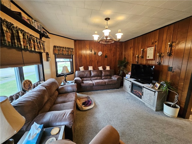 carpeted living room with a chandelier, ornamental molding, and wooden walls