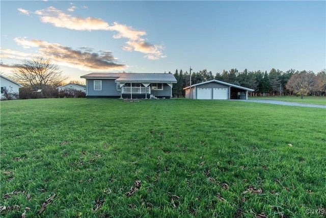 ranch-style home featuring a porch, a garage, an outdoor structure, and a lawn