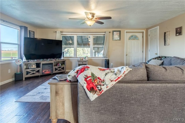 living room featuring a wealth of natural light, ceiling fan, and dark wood-type flooring