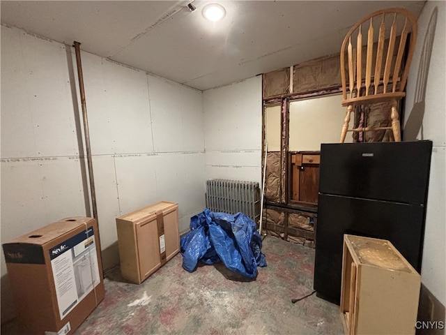 basement with black fridge, radiator, and heating unit