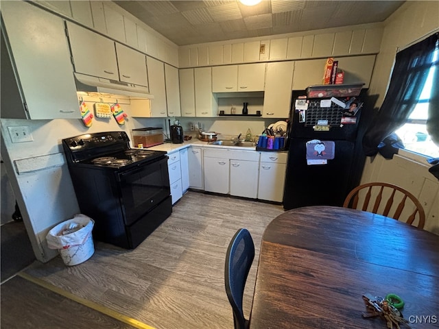 kitchen featuring sink, light hardwood / wood-style floors, white cabinetry, and black appliances