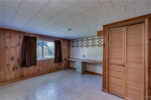 unfurnished office featuring wooden walls and built in desk