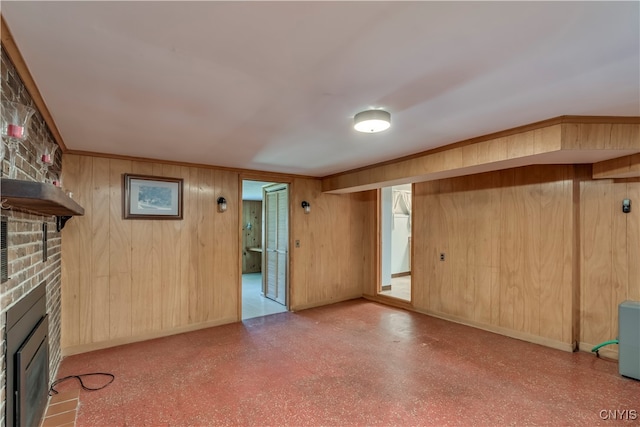 unfurnished living room with crown molding, a large fireplace, and wooden walls