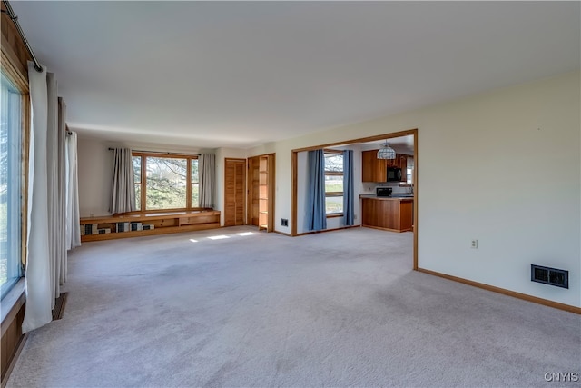 unfurnished living room with light carpet and plenty of natural light