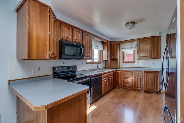 kitchen featuring sink, stainless steel appliances, decorative backsplash, kitchen peninsula, and light wood-type flooring