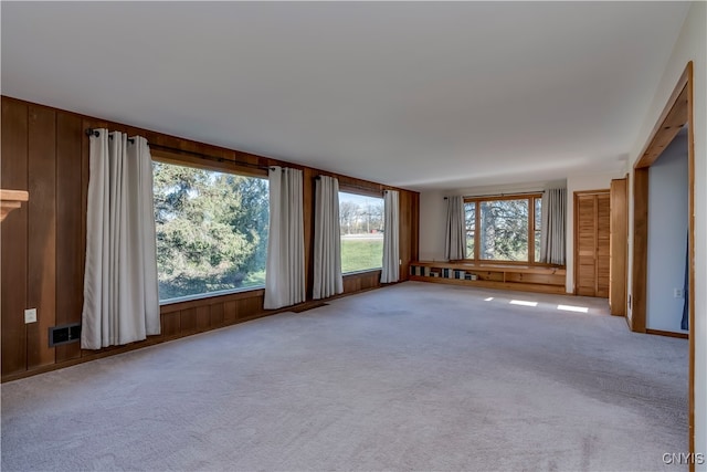 unfurnished living room with light carpet and wooden walls