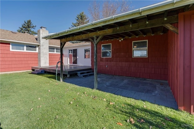 rear view of house with a yard, a deck, a patio area, and a chimney