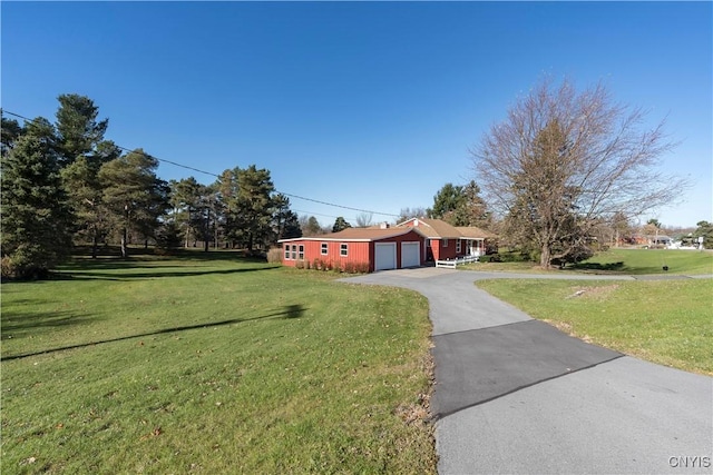 ranch-style home featuring aphalt driveway, an attached garage, and a front lawn